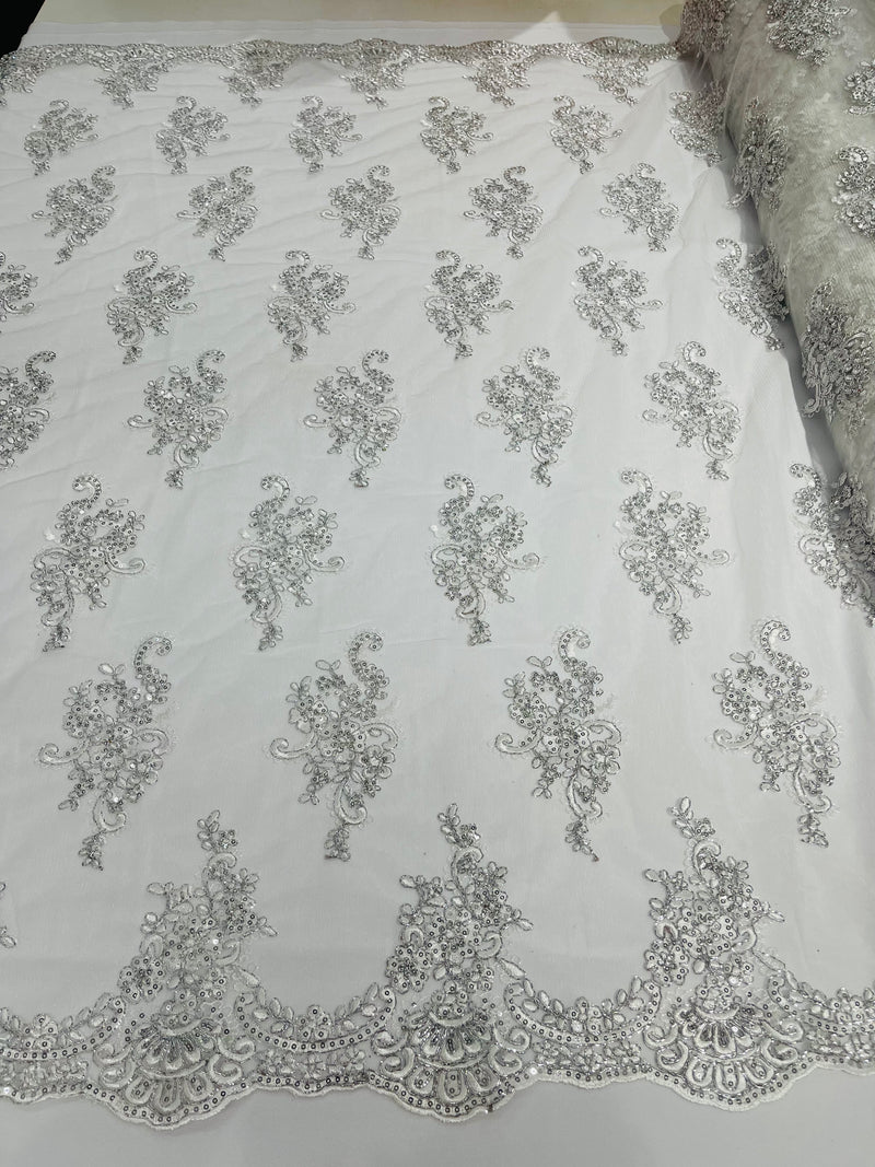 White/ silver metallic floral design embroidery on a mesh lace with sequins and cord-sold by the yard.