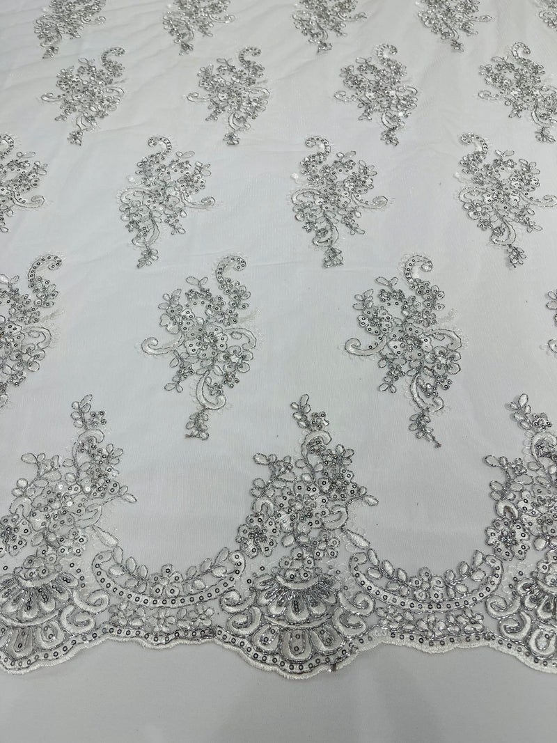 White/ silver metallic floral design embroidery on a mesh lace with sequins and cord-sold by the yard.